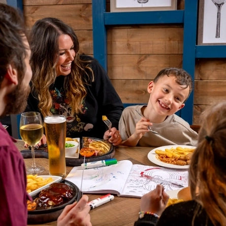 a family sitting at a table of a pub eating food