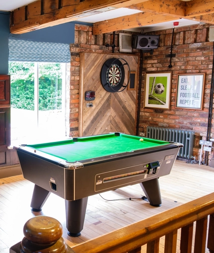 An image of the interior seating and games area with pool table and dartboard at The Guild.