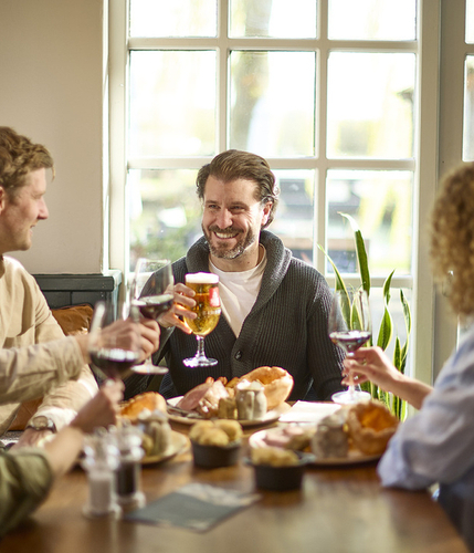 An image showing 4 people sat at a table within the interior restaurant seating area enjoying various food dishes and drinks at a Chef & Brewer venue.