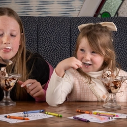 Two children enjoying an ice-cream sundae served at a Flaming Grill venue.