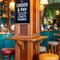 The bar and interior restaurant seating area of The Fountains Abbey, with wooden and metal tables, upholstered seating and a TV on the wall.