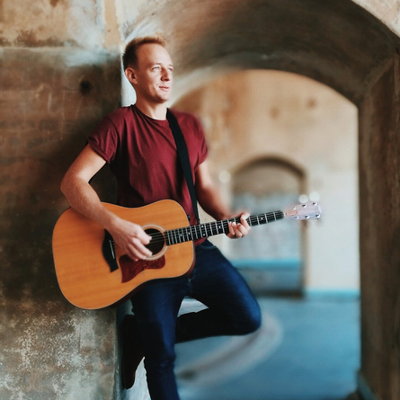 An image of Will Tierney stood inside a building playing guitar to advertise a live music event at The Cart & Horses.