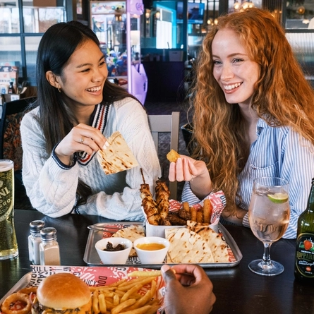 Friends enjoying a meal and drinks in the interior restaurant from the new Spring/Summer menu at Flaming Grill.