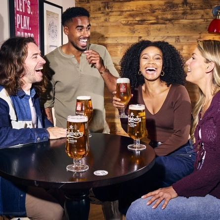 An image showing 4 friends at a table enjoying drinks within the interior seating area at a Flaming Grill venue.