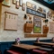 An interior restaurant seating area at the Old School House, with upholstered bench seats, and artwork and photographs on the wall showcasing the history of the venue.