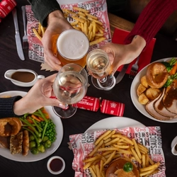 plates of food and a few drinks sitting on a wooden table of a pub