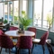 An interior restaurant seating area at the Golden Hind, with upholstered chairs, large windows, and potted plants.