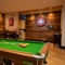 The interior pub gaming area at the Arch & Anchor, with a pool table, dartboard, TVs on the wall, and a restaurant table. 