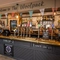 A close up view of the bar inside The Woolpack Inn in Norwich, with golden drinks trays and a gold hand rail on the counter, and bunting hanging overhead.